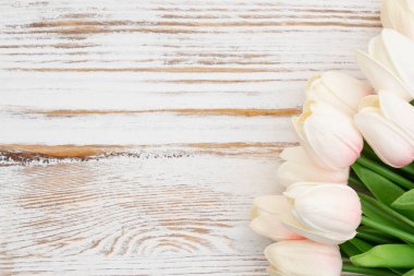 Eskimiş ahşap arka planda açık beyaz ve pembe laleler.