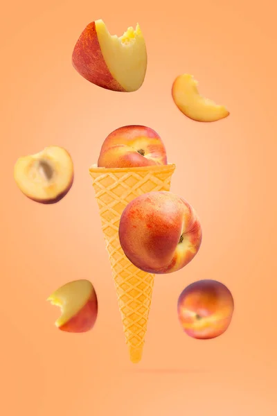 Falling ice cream cone with peach fruits. Seven flying whole peaches on colored table with clipping path as package design element and advertising. Selective focus.
