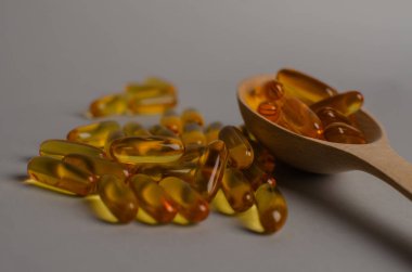 Tahta kaşıkta Omega 3 kapsülleri, sert gölgeler, tasarımınız için kopyalama alanı. Morina yağı kapsülleri masada. Sağlıklı yaşam tarzı kavramı. Yüksek kalite fotoğraf