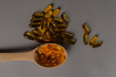 Tahta kaşıkta Omega 3 kapsülleri, sert gölgeler, tasarımınız için kopyalama alanı. Morina yağı kapsülleri masada. Sağlıklı yaşam tarzı kavramı. Yüksek kalite fotoğraf