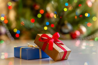 Hediye kutuları ve arka planda bulanık parti ışıkları ve oyuncak topları olan Noel ağacı. Noel kutlaması.