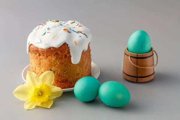 Sweet Easter cake with a daffodil flower and colorful Easter eggs on the gray background.