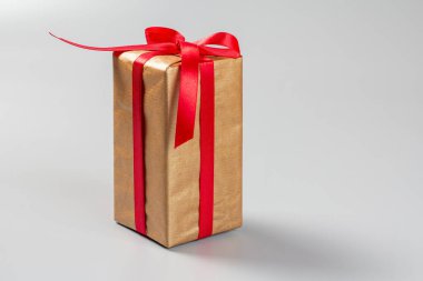 Gri arka planda kırmızı kurdeleyle bağlanmış bir hediye kutusu. Tebrik kartı kavramı.