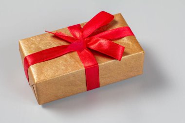 Gri arka planda kırmızı kurdeleyle bağlanmış bir hediye kutusu. Üst Manzara. Tebrik kartı kavramı.
