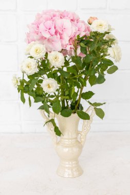 Güzel bir buket pembe seramik vazoda beyaz çiçekler ve arka planda beyaz bir duvar..