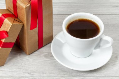 Gri ahşap arka planda beyaz kahve ve hediye kutuları..