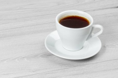 Gri ahşap masanın üzerinde beyaz kahve fincanı.