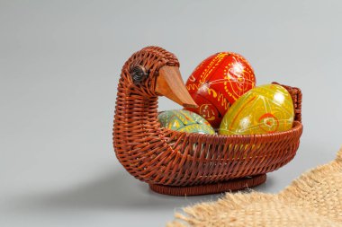 Hasır sepete boyanmış Paskalya yumurtaları gri arka planda..