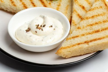 Peynir soslu beyaz porselen kase ve tabakta tost. Üst görünüm.