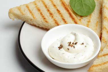 Peynir soslu beyaz porselen kase ve tabakta tost. Üst görünüm.