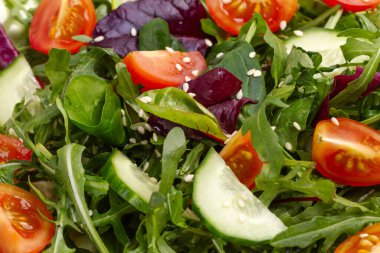 Taze domates, salatalık, roka, fesleğen, ıspanak ve susamlı salata. Sağlıklı sebze diyeti. Yakın çekim görünümü.