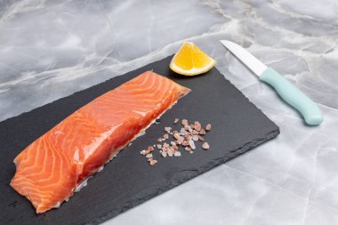 Kesme tahtasının üzerinde tuzlu ve limonlu çiğ somon balığı filetosu. Üst görünüm.