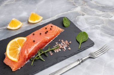 Çiğ somon balığı filetosu roka, fesleğen yaprağı, baharat ve limon dilimleri. Üst görünüm.