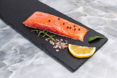 Çiğ somon balığı filetosu roka, fesleğen yaprağı, baharat ve dilimlenmiş limon. Üst görünüm.