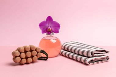 Kişisel hijyen ürünleri. Sabun, orkide çiçekli bir şişe duş jeli ve pembe arka planda bir havlu. Spa ve sağlık seti.
