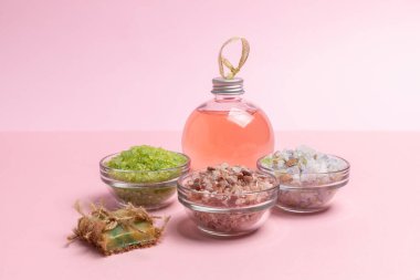 Kişisel hijyen ürünleri. El yapımı sabun, deniz tuzu ve pembe arka planda bir şişe duş jeli. Spa ve sağlık seti.