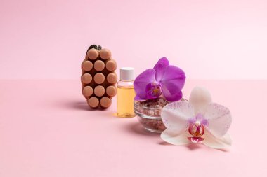 Kişisel hijyen ürünleri. Deniz tuzu, ev yapımı sabun, aromatik yağlı bir şişe ve pembe arka planda orkide çiçekleri. Spa ve sağlık seti.