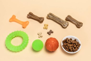 Dry food and playful toys for dogs. Granulated animal feeds in a bowl and artificial dog chew bone food with vitamins. Balls, a rubber chewing bone and a ring. Top view. clipart