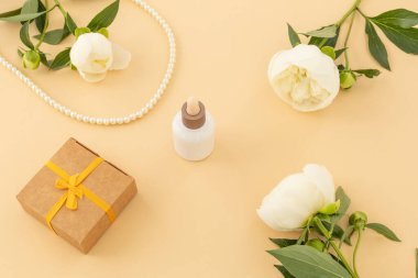 Yüz serumu, hediye kutusu ve bej arka planda boncuklar. Kadın kozmetik ve aksesuarları. Üst görünüm.