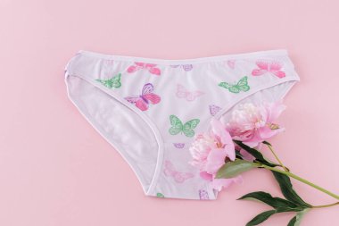 Pembe arka planda şakayık çiçekleri olan kısa bikinili pamuk külot. Kadın iç çamaşırı. Üst görünüm.