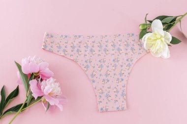 Pembe arka planda şakayık çiçekleri olan minimalist tanga tarzı pamuk külot. Kadın iç çamaşırı. Üst görünüm.