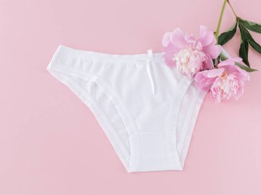 Pembe arka planda şakayık çiçekleri olan kısa bikinili pamuk külot. Kadın iç çamaşırı. Üst görünüm.