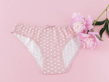 Pembe arka planda şakayık çiçekleri olan kısa bikinili pamuk külot. Kadın iç çamaşırı. Üst görünüm.