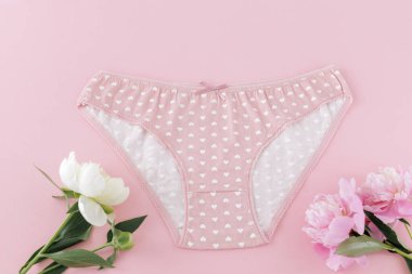 Pembe arka planda şakayık çiçekleri olan kısa bikinili pamuk külot. Kadın iç çamaşırı. Üst görünüm.