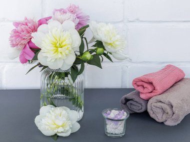 Yüz ve vücut bakımı ürünleri. Yumuşak havlular, deniz tuzu ve cam vazoda şakayık çiçekleri. Spa ve vücut bakımı seti. Üst görünüm.