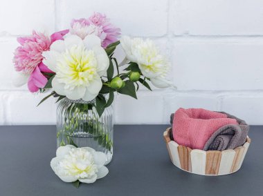 Yüz ve vücut bakımı ürünleri. Tahta sepetteki yumuşak havlular ve cam vazodaki şakayık çiçekleri. Spa ve vücut bakımı seti. Üst görünüm.