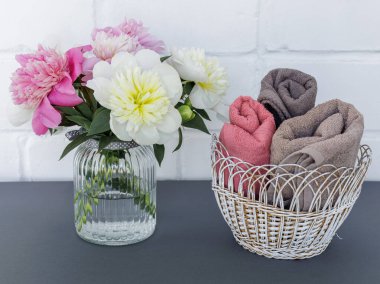 Yüz ve vücut bakımı ürünleri. Hasır sepette yumuşak havlu ve cam vazoda şakayık çiçekleri. Spa ve vücut bakımı seti. Üst görünüm.