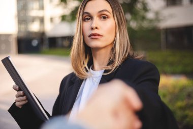 Kendine güvenen iş ortağı, şehir merkezindeki ofisin yakınındaki açık alanda yapılan görüşmeden sonra tokalaşıyor. Ciddi güzellik işkadını şirket temsilcisiyle anlaşma yapıyor. Tableti tut, tokalaş..
