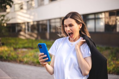 Güzel, kısa saçlı, ceketi omuzunda tutan kadın. Şaşırmış bir kız cep telefonuna bakıp bağırıyor, ofisin yanında el ele tutuşuyor. Mutlu kadın cep telefonunda iyi haberler arıyor..