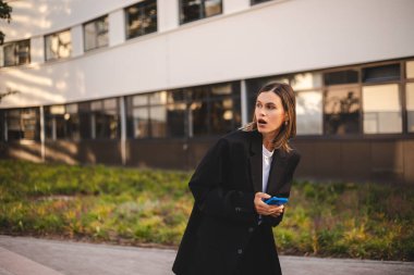 İş kadını kısa saçlı kadın ceket giyiyor, ofisin yanında duruyor, arıyor, bekliyor ya da arıyor. Sakin bir kadın cep telefonunu tutar. İş toplantısı. Kız buluşur ve heyeti bekler.