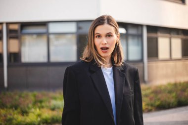 Aman Tanrım, vay canına. Şaşırmış genç Kafkas iş kadını başarılı bir kız ağzı açık kameraya bakıyor şaşırmış bir şekilde iş merkezinin yanında zaferden mutlu bir şekilde duruyor..