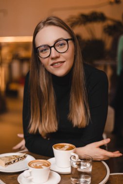 Lokanta kafesinde kahve içerken sevgilisini dinleyen bir kadına aşık olmak ilgini çekiyor. Gözlük takan, gülümseyen bir kız..