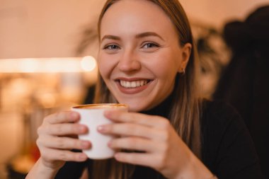 Kapalı gözlerle gülümseyen muhteşem kadının portresi restoranda dinlenirken fincandan kapuçino kokluyor ve içiyordu..