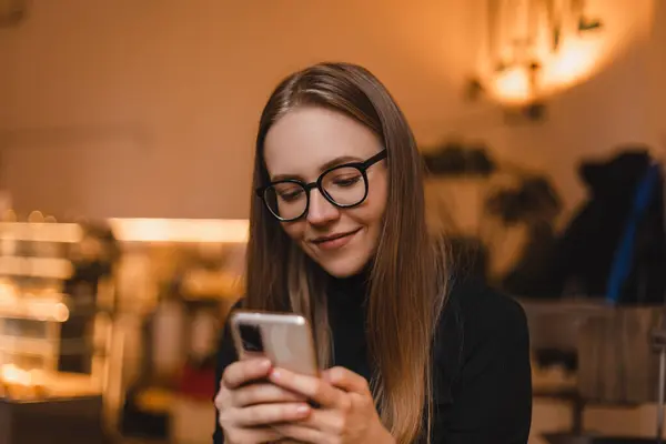 Güzel gülüşü olan, kafede dinlenirken cep telefonundan iyi haberler okuyan, Kafkasyalı mutlu bir kadın, boş zamanlarında cep telefonundan resimlerini seyrediyor..