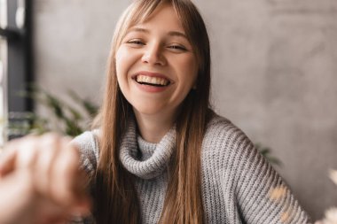 Erkek avucunun içinde kadın avucu. Romantik randevu konsepti. El ele tutuşurken kahve içen bir çift. Kadın gülüyor, sevgilisine bak. Gri kazak giy, mutlu görün, gülümse..