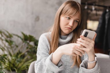 Yakın plan portre üzgün, kuşkucu, mutsuz, ciddi bir kadının telefonda konuşması kafede oturmaktan rahatsız edici. Negatif insani duygu yüz ifadesi.