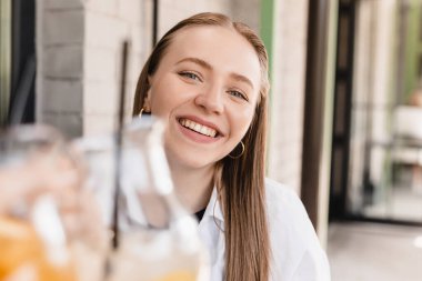 Kutlama için kadeh kaldıran arkadaşlar. Limonata ve portakal içen kadınlar. Toplantıyı kutluyor. Sarışın kadın bardakları tokuşturuyor açık kafede oturuyor, mutlu..