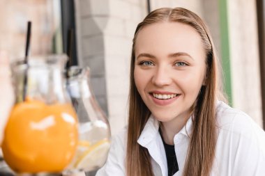 Kutlama için kadeh kaldıran arkadaşlar. Limonata ve portakal içen kadınlar. Toplantıyı kutluyor. Sarışın kadın bardakları tokuşturuyor açık kafede oturuyor, mutlu..