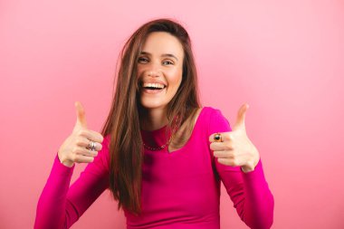 İyimser esmer kadın başparmak kaldırıyor. Harika bir jest yapıyor. İyi iş çıkardığını söylüyor, olumlu geri bildirim veriyor..