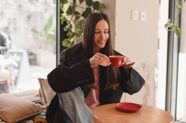 Kafede kahve içen düşünceli esmer kadın, yaşam tarzı, kahve, iletişim ve yerel iş, değişmemiş. Mutlu kız cappuccino içer, kafeteryada dinlenir.