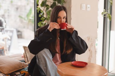 Kafede kahve içen düşünceli esmer kadın, yaşam tarzı, kahve, iletişim ve yerel iş, değişmemiş. Mutlu kız cappuccino içer, kafeteryada dinlenir.