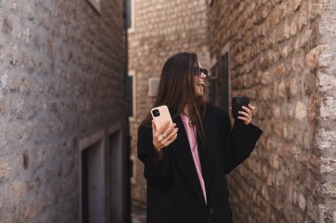 Mutlu gülümseyen esmer kadın heyecanlı yüz ifadesiyle akıllı telefonu tutuyor, oynadığına, piyangoyu kazandığına, iyi haberler okuduğuna inanamıyor, falına inanamıyor. Kucaklaşmaya hazır ol..