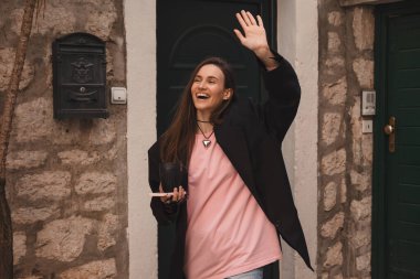 Gülümseyen genç bir kadın yeni komşularına güler yüzle el sallıyor. Kız evden çıkar ve elini sallar. Siyah ceket giyen bir kız, elinde bardakla telefon eder, arkadaşlarıyla buluşur..