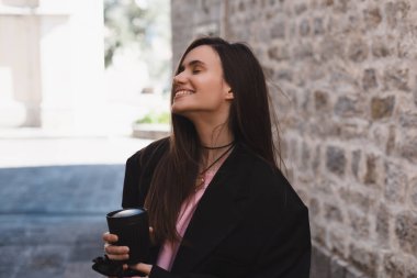 Şehir parkında yürüyen çekici esmer kadın. Siyah ceket giyen, mutlu görünen ve gülümseyen bir kız. Caddeye çıkan bir kadın, eski bir kasabada geri döner. Kahve içmek için elinde bardak tutan kız.