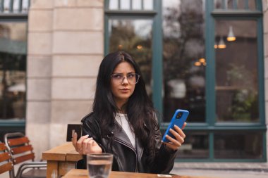 Çevrimiçi ödeme sorunu. Banka kartının engellenmesine şaşıran genç bayan. Kafe 'de cep telefonuyla internet alışverişinde kredi kartından çok fazla para harcayan kafası karışık bir kadın var..