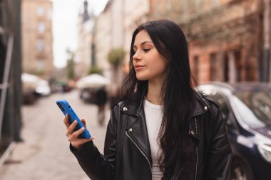 Genç, şık bir bayan öğrenci akıllı telefondan mesaj yazıyor. Eski şehir caddesinde yürüyor, hipster turistleri şehirde geziyor ve cep telefonu kullanarak seyahat planlıyor, kız sohbeti yapıyor, haberleri okuyor, mutlu görünüyor..